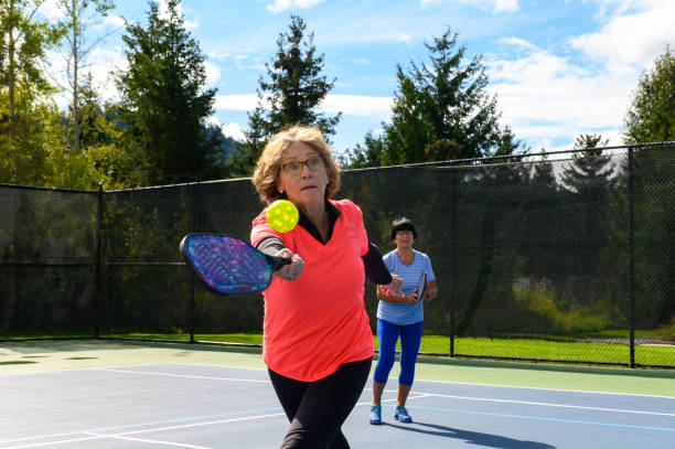 Active seniors playing pickleball at a public court Senior women playing pickleball. Active seniors living a healthy lifestyle. Staying active in retirement. tennis senior adult adult mature adult stock pictures, royalty-free photos & images