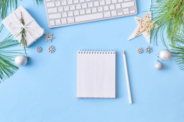 Mockup white notebook with pine branches and keyboard, christmas decorations on a blue background