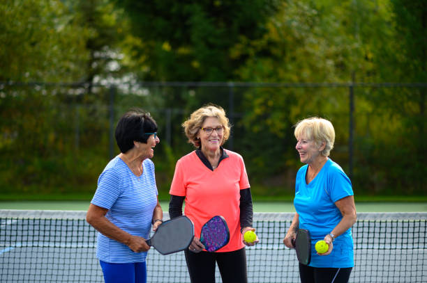 Active seniors bonding at the tennis court stock photo