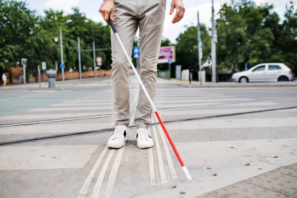 Midsection of young blind man with white cane walking across the street in city. Midsection of young unrecognizable blind man with white cane walking across the street in city. blind persons cane stock pictures, royalty-free photos & images