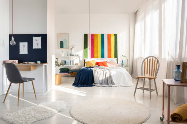 istock White bedroom interior with workspace with chair and rainbow colored bedhead 1181026264