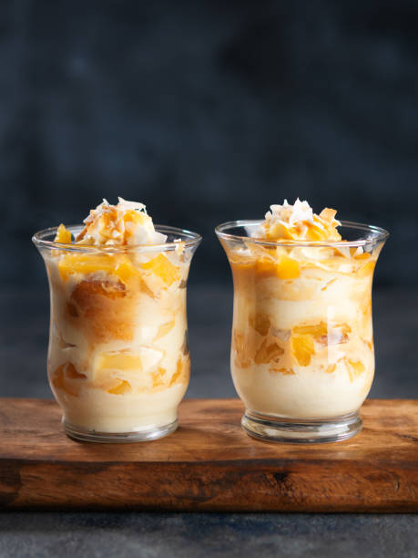 Pineapple, peach, Coconut Trifle dessert mouse in a glass on a dark background with copy space. Vegan recipe dessert concept. Selective focus. Pineapple, peach, Coconut Trifle dessert mouse in a glass on a dark background with space for text. Vegan recipe dessert concept. Selective focus. trifle stock pictures, royalty-free photos & images