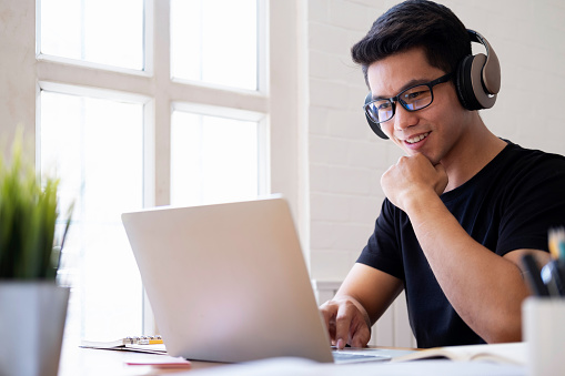 Un estudiante joven estudia en casa usando computadora portátil y aprendiendo en línea. photo