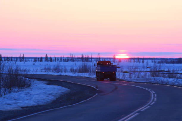 Winter landscape with a car on a winter road among the Yamal tundra in Russia Truck rides on the road in the background of sunset in winter among the tundra of Northern Siberia all weather running track stock pictures, royalty-free photos & images