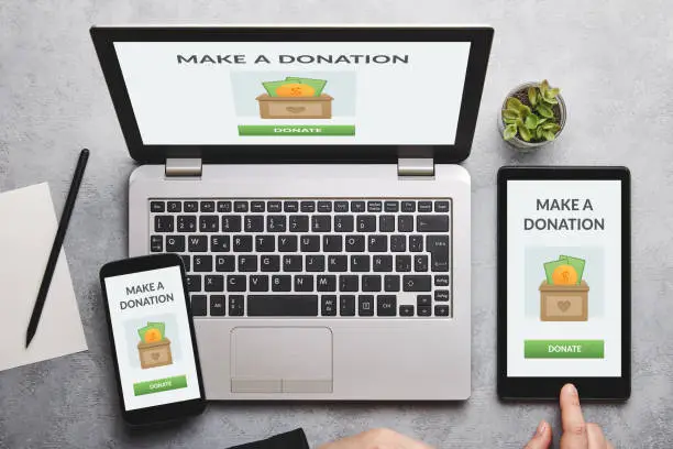 Donation concept on laptop, tablet and smartphone screen over gray table. Top view