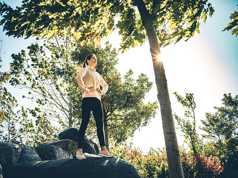 Millennial woman exercising in the city park on the sunny morning in the fall.