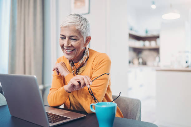 istock Smiling senior woman using laptop at home 1181035356