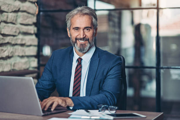 Mature businessman with a laptop Smiling mature businessman in the office mid adult men stock pictures, royalty-free photos & images