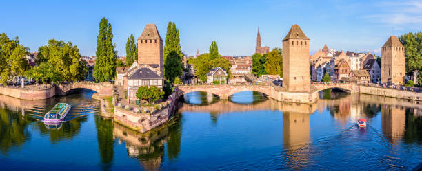 Panoramic view of the Ponts Couverts in Strasbourg, France. Panoramic view of the Ponts Couverts on the river Ill at the entrance of the Petite France historic quarter in Strasbourg, France, with a tour boat and an electric renting boat cruising on the canals. notre dame de strasbourg stock pictures, royalty-free photos & images