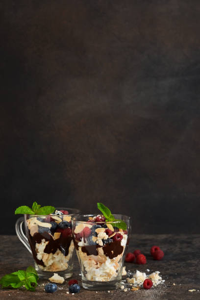 Dessert in a glass with chocolate, meringues and berries on a dark background. Close up view. Dessert in a glass with chocolate, meringues and berries on a dark background. Close up view. yogurt fruit biscotti berry fruit stock pictures, royalty-free photos & images