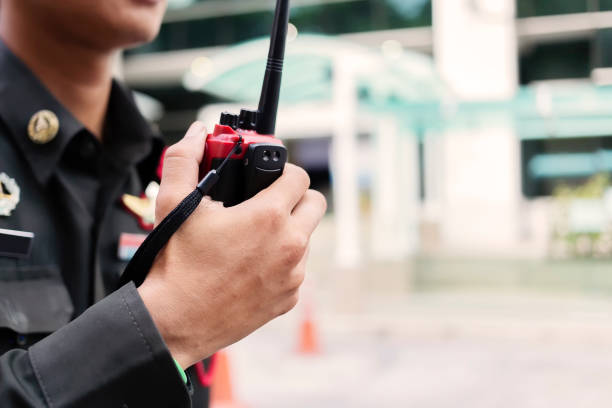 el guardia de seguridad utiliza la comunicación por radio para facilitar el tráfico. los oficiales de tráfico usan walkie talkie para mantener el orden en el estacionamiento en tailandia. - oficio de seguridad fotografías e imágenes de stock