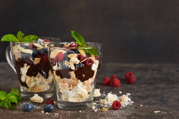 Dessert in a glass with chocolate, meringues and berries on a dark background. Close up view. Dessert in a glass with chocolate, meringues and berries on a dark background. Close up view. yogurt fruit biscotti berry fruit stock pictures, royalty-free photos & images