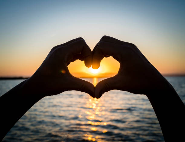 istock Hands forming heart shape against golden sunset 1181042116