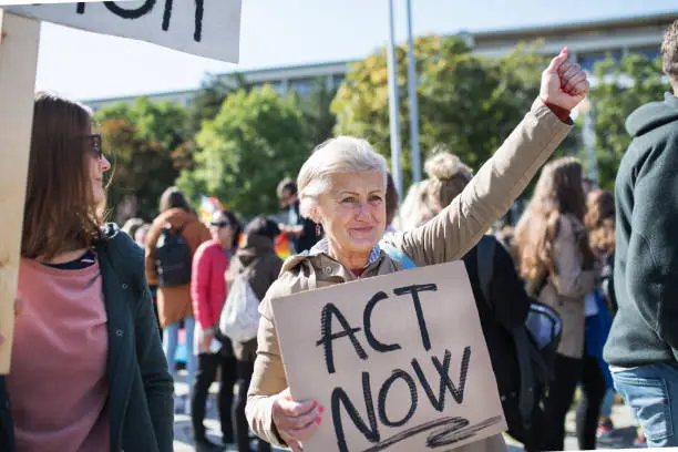 Photo of Senior with placard and poster on global strike for climate change.