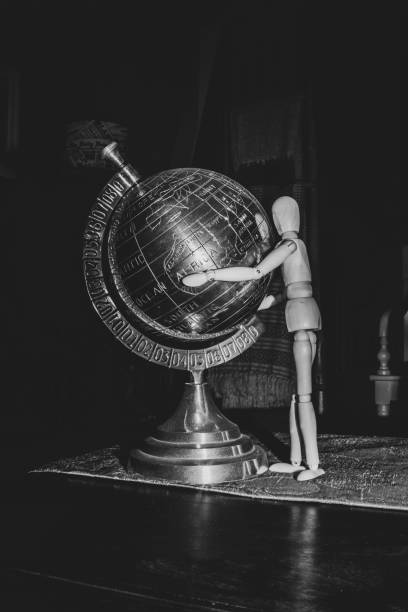 istock Wooden Human Manikin posing with an ornamental silver world globe 1181051027