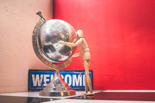 istock Wooden Human Manikin posing with an ornamental silver world globe 1181051049
