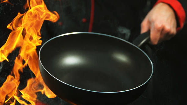 istock Closeup of chef holding empty wok pan with flames. 1181054861