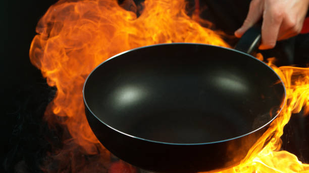 istock Closeup of chef holding empty wok pan with flames. 1181054881