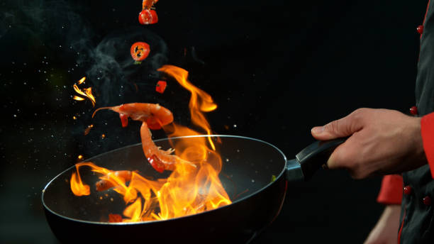 closeup of chef holding wok pan with falling prawn - shrimp pan cooking prepared shrimp imagens e fotografias de stock