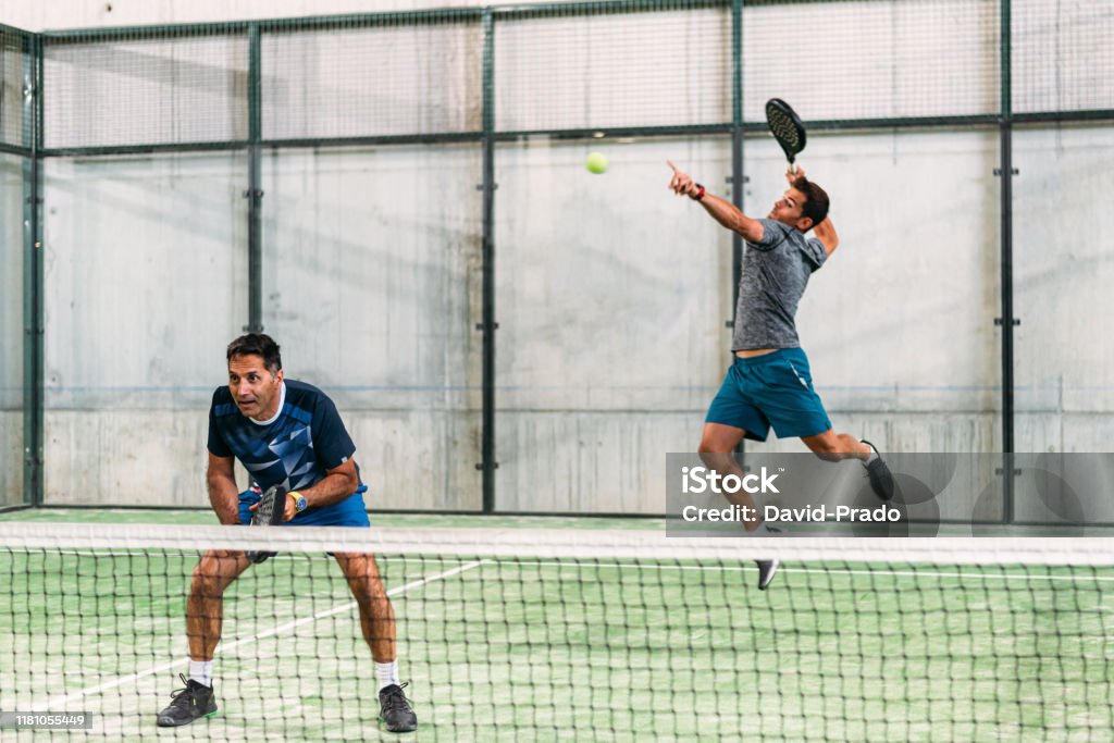 Men playing padel two padel player playing padel in a green grass padel court indoor behind the net Padel Stock Photo