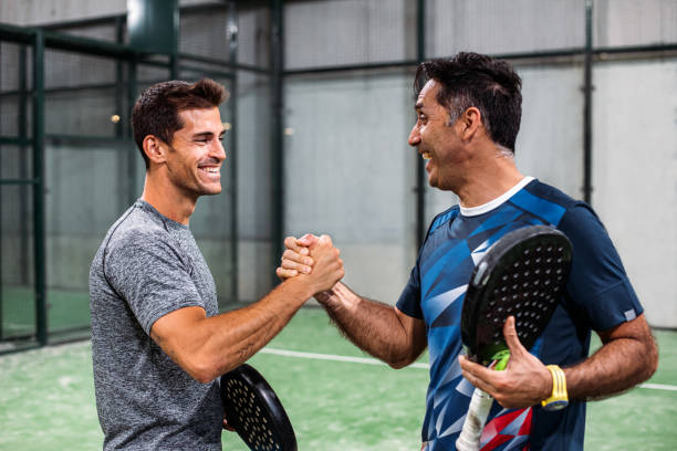 dos jugadores de pádel estrechando las manos después de ganar un partido de pádel - tennis court tennis net indoors fotografías e imágenes de stock