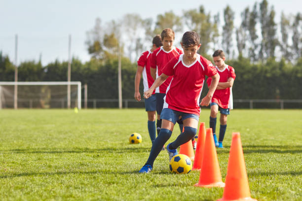 jóvenes futbolistas españoles regateando alrededor de los conos en el taladro - nivel júnior fotografías e imágenes de stock