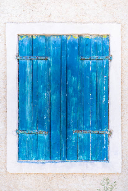 White wall with blue window and closed shutters. Greek style.