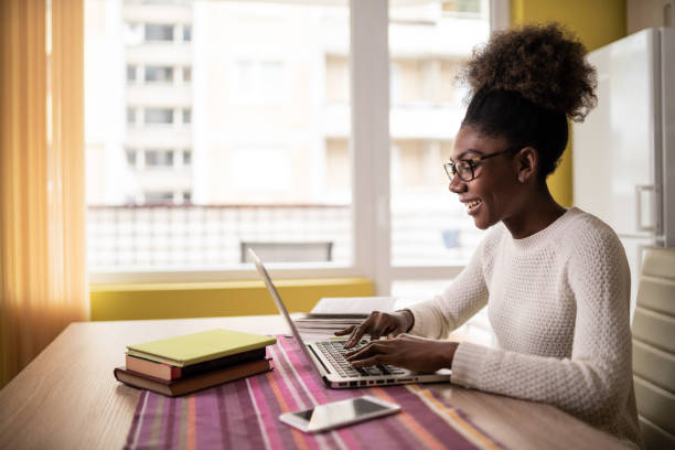 afro mujer sentada en casa usando computadora portátil y estudiando - education school computer teacher fotografías e imágenes de stock