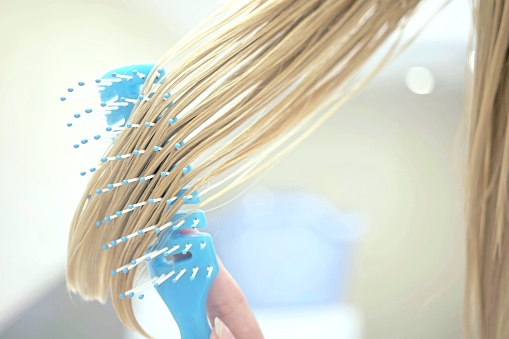 lock of wet blond hair combed by a blue comb