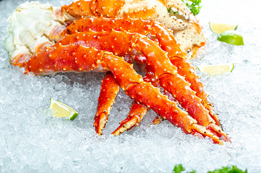 large red Kamchatka crab claws phalanx legs tentacles, lies on ice, cherry, slices of lemon and lime are sliced round, lie around, with fresh herbs, light, top side view, around