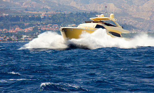 La Spezia, Italy - July 10, 2022: White and black luxury yacht or speedboat in motion in the blue Mediterranean sea, with six people aboard on a sunny summer day. Gulf of La Spezia, La Spezia, Liguria, Italy, Europe.