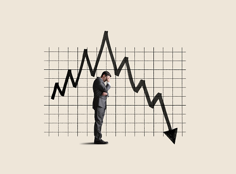 A businessman stands next to a chart that shows performance declining as he places his head in his hands because he can't bare to watch.