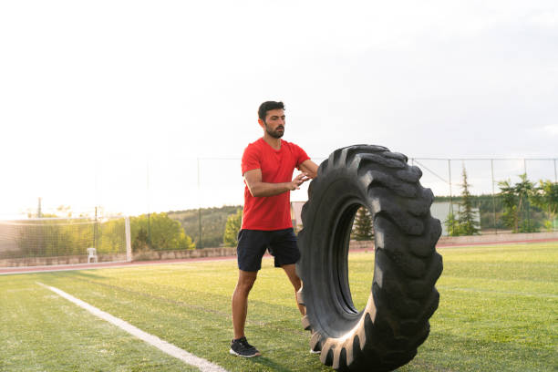 istock Young athletic man training outdoors. Athlete doing exercise with truck tire, Young adult doing a fitness workout 1181077148