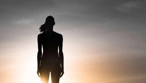 istock Woman standing at sunset 1181078470