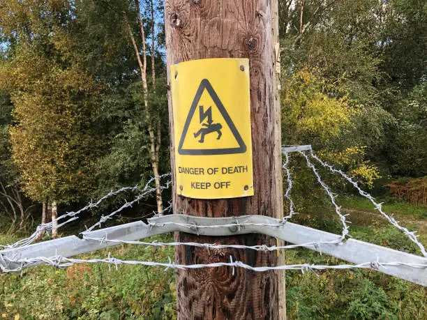 Photo of Electrocution and danger sign and barbed wire on an electricity post