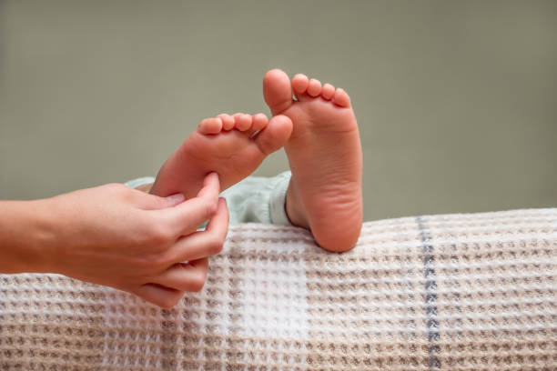 sfondo piedi solletico. toccare i piedi del bambino con le dita. massaggio di piedi, gambe. tacchi e dita dei piedi sul letto. tacchi e piedi. toccando le mani, solleticando i piedi del bambino. concetto di parti del corpo. tocco delicato - tickling foto e immagini stock