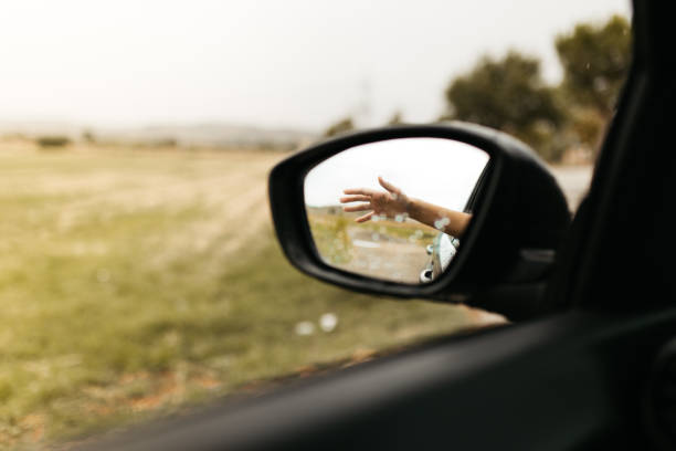 istock Hand touching rain drops. Mirror seen through the glass. Wet car window. Close up rain drop. Car view see the mirror. Rainy day. 1181089708