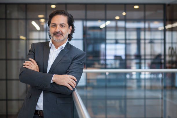 alto ejecutivo hombre latino con traje azul y brazos cruzados - director ejecutivo de empresa fotografías e imágenes de stock