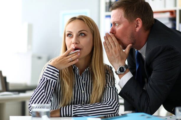 empleado masculino compartiendo algunos conocimientos secretos con colegas femeninas - whispering couple discussion smiling fotografías e imágenes de stock