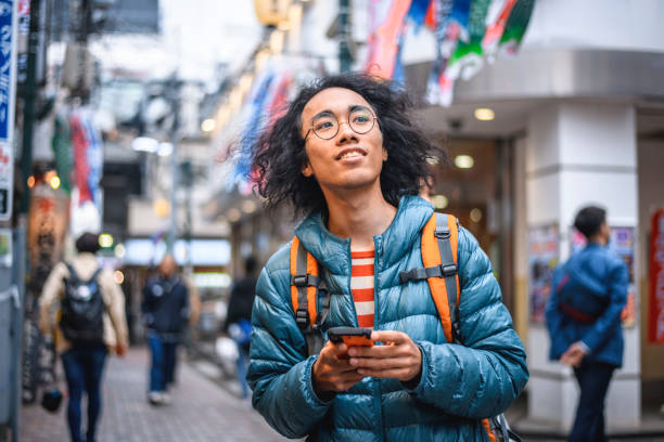 istock Smiling Japanese Backpacker Consulting Smartphone in Tokyo 1181099466