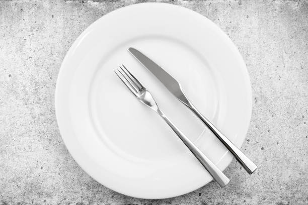 istock Table setting. Empty plate, knife and fork on a light concrete background. The fork and knife lie in parallel on a plate, the meal is over. Top view and flat lay with copy space. 1181100886