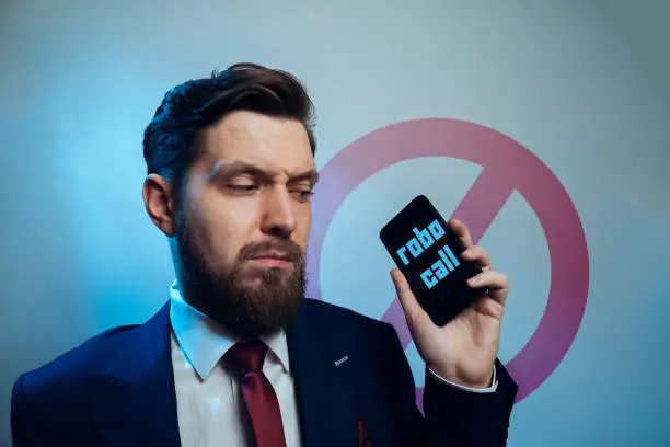 Photo of Man frowning receiving telemarketing robo call