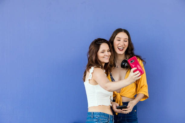 istock Best Friends Taking Selfies Against Purple Wall 1181115879