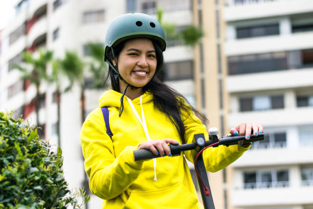 Laughing young woman with helmet on an electric scooter. stock photo