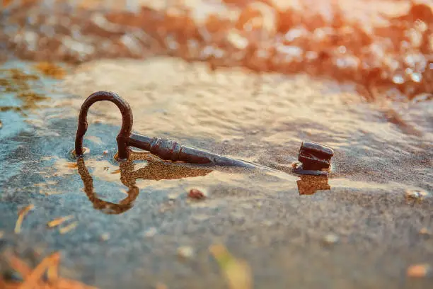 Photo of An old lost key in the sand is a newfound opportunity. The concept of success, luck and unexpected wealth