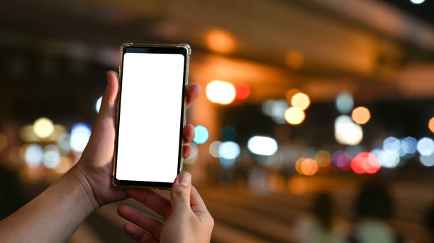 istock Mockup smartphone on hands with empty screen and bokeh on blur night city background. 1181124692
