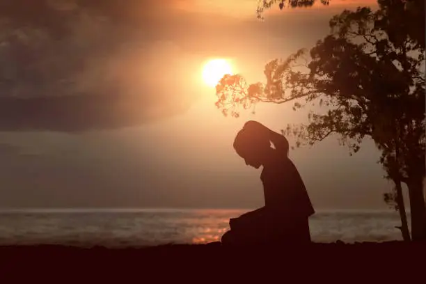 Photo of Silhouette of woman read the bible on the beach