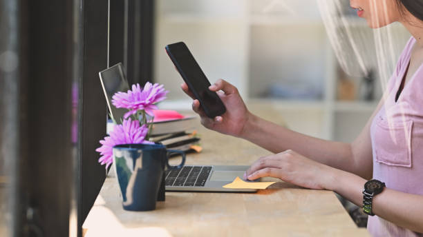 istock Cropped shot young woman using laptop computer and smartphone. 1181124980