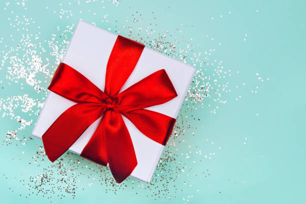 istock Gift box with red bow on green mint background with delicate golden sparkles. 1181133132