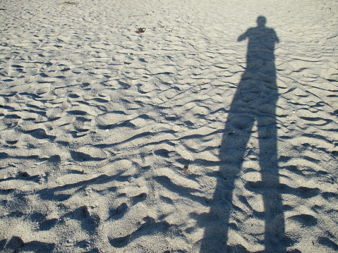 Long shadow of a person standing on the sand Footprints